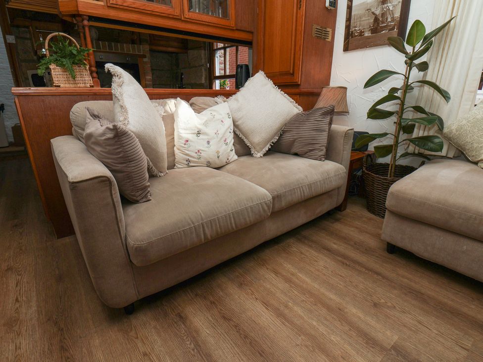 A sofa with cushions and an indoor plant at Bishop's Cottage in Whitby