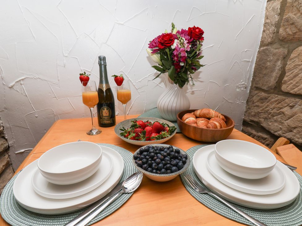 A dining table set with champagne, fruit, and pastries at Bishop's Cottage in Whitby