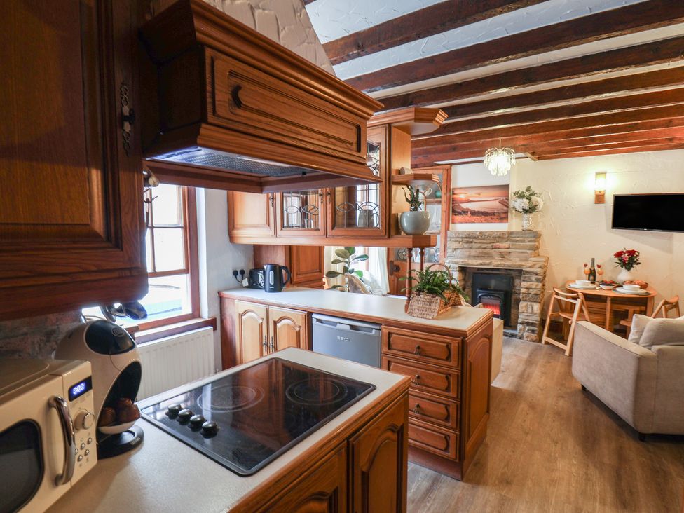 A kitchen with wooden cabinets and appliances at Bishop's Cottage in Whitby