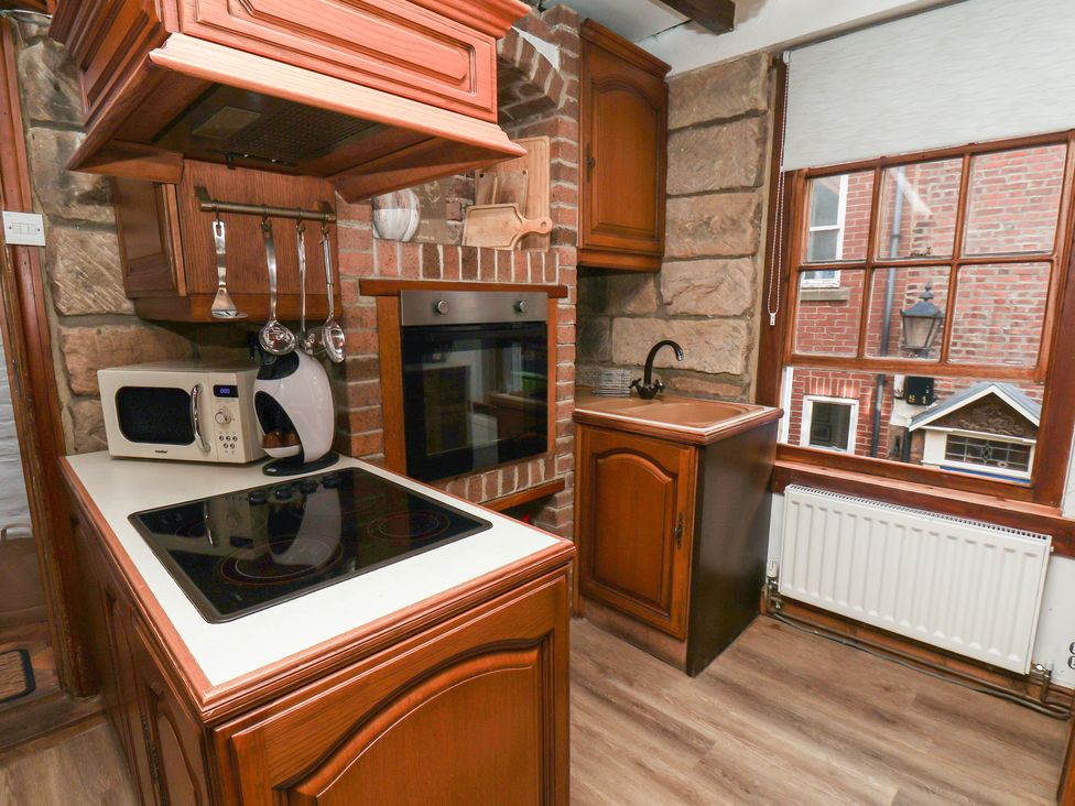 A kitchen with a microwave, kettle, cooker, and sink at Bishop's Cottage in Whitby