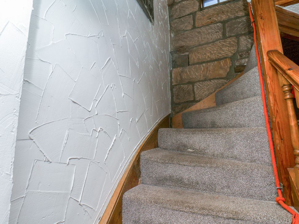 A staircase with carpet and a stone wall at Bishop's Cottage in Whitby