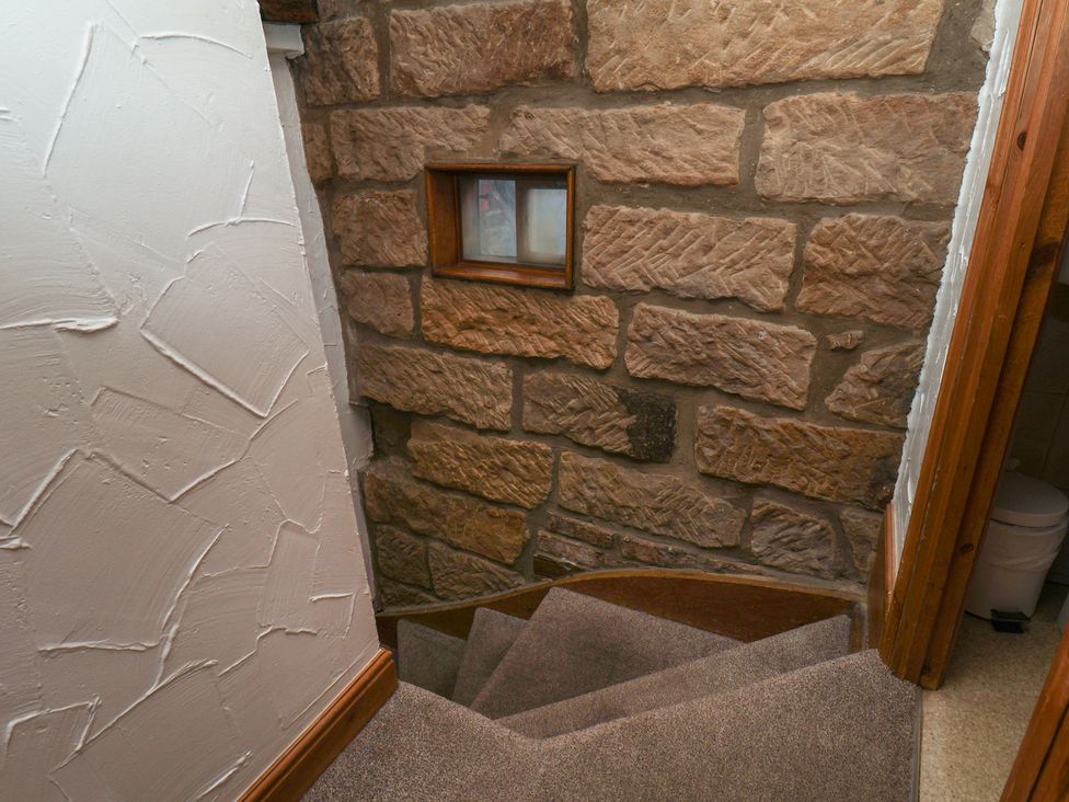 A staircase with stone walls and a window at Bishop's Cottage in Whitby