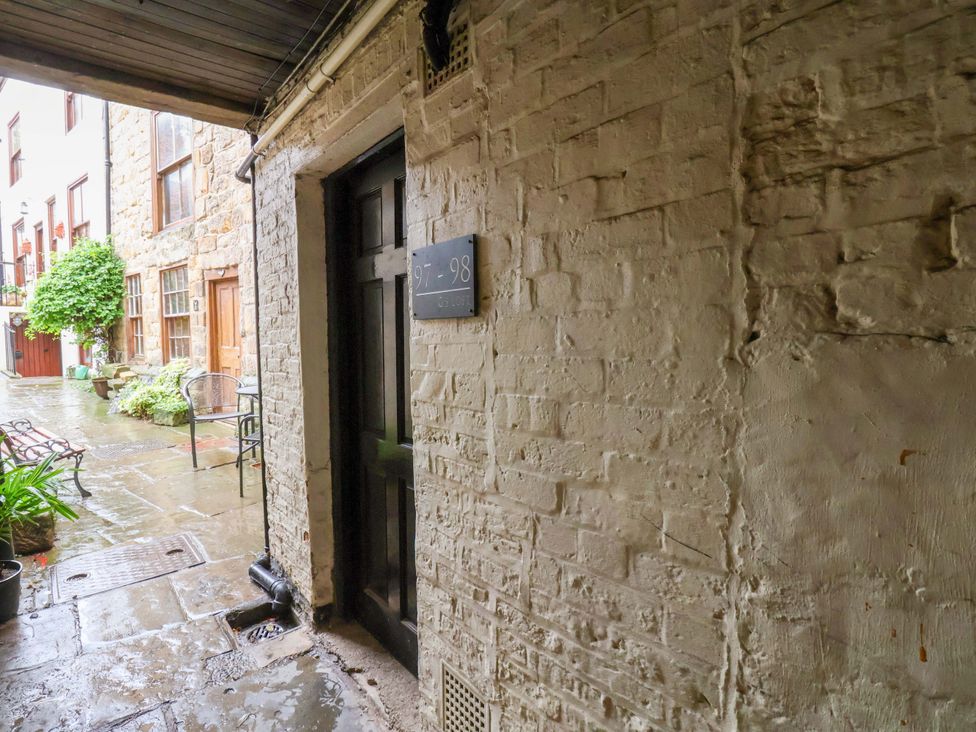 An outdoor corridor with a door and brick wall at G's Loft in Whitby