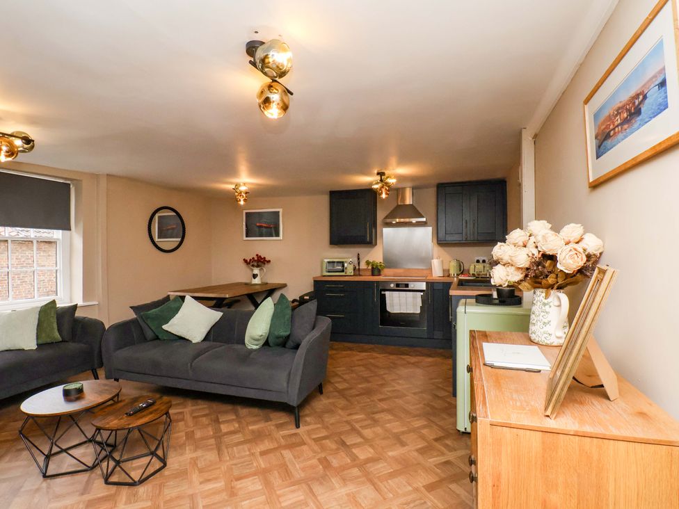 A living room with a kitchen area and seating at G's Loft in Whitby