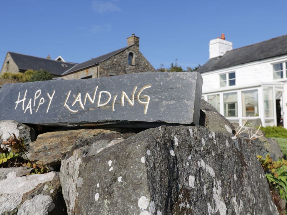 A stone sign reading Happy Landing in front of a house at Happy Landing in Harlech