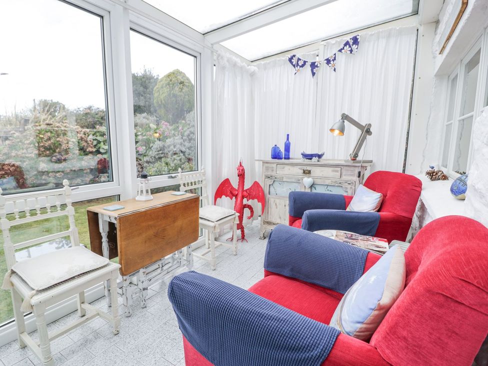 A conservatory with seating and a wooden table at Happy Landing in Harlech