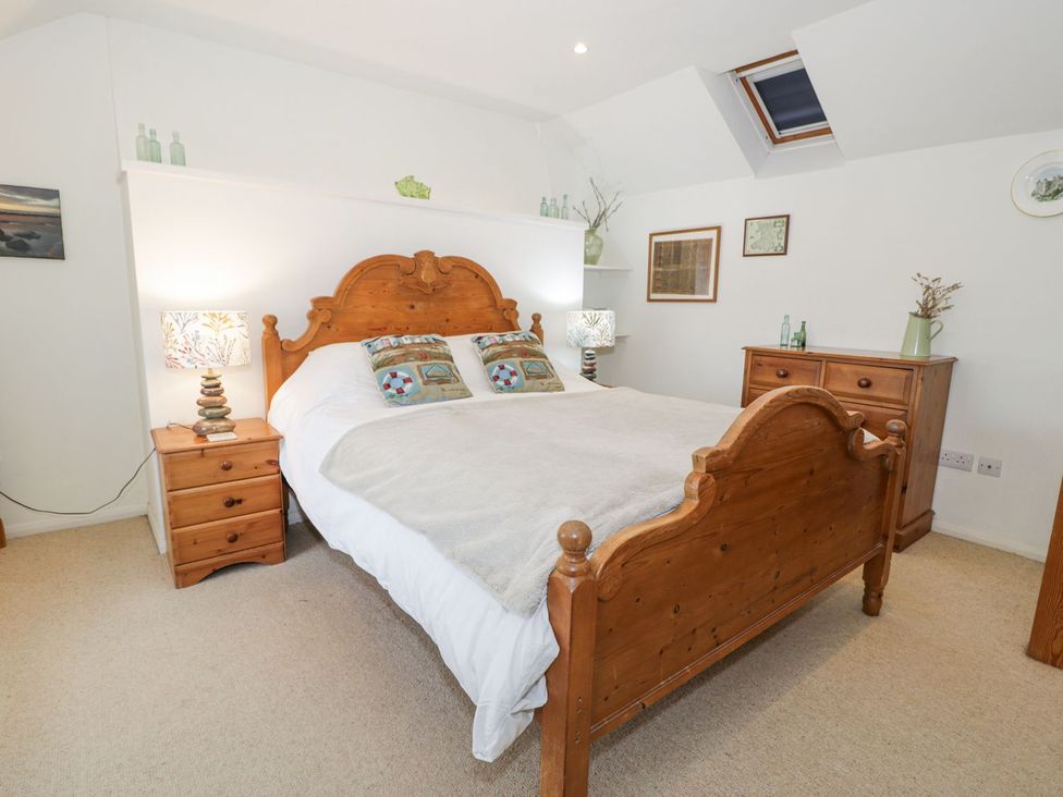 A bedroom with a wooden bed and nightstand at Happy Landing in Harlech