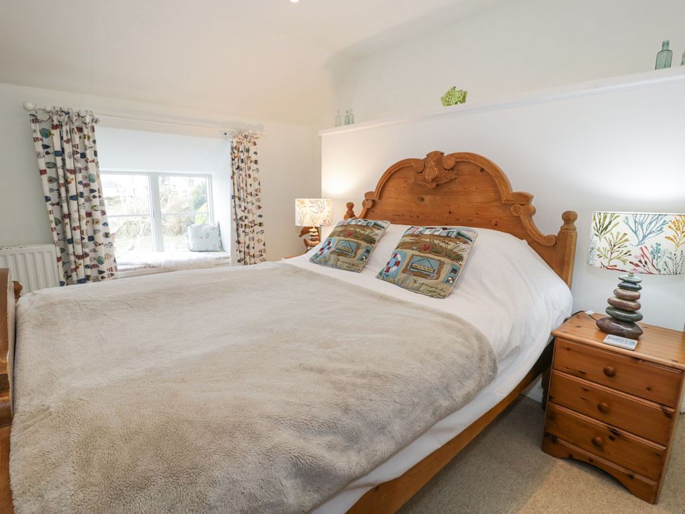 A bedroom with a wooden bed and bedside table at Happy Landing in Harlech