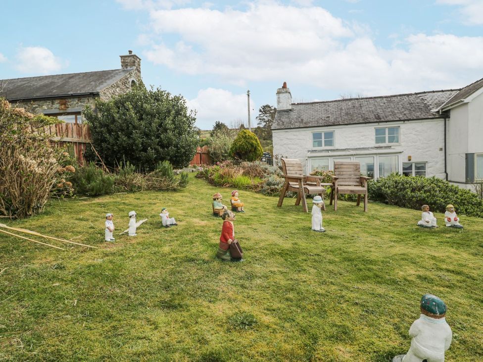 A garden with decorative figurines and wooden chairs at Happy Landing in Harlech