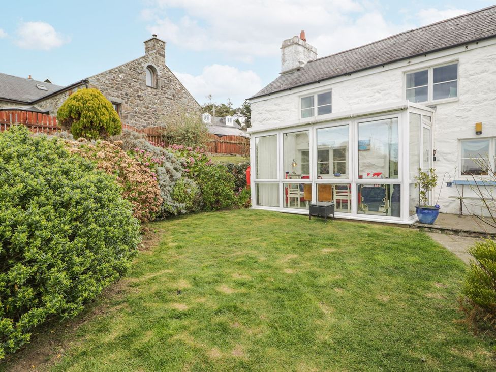 A garden with a glass room and shrubs at Happy Landing in Harlech