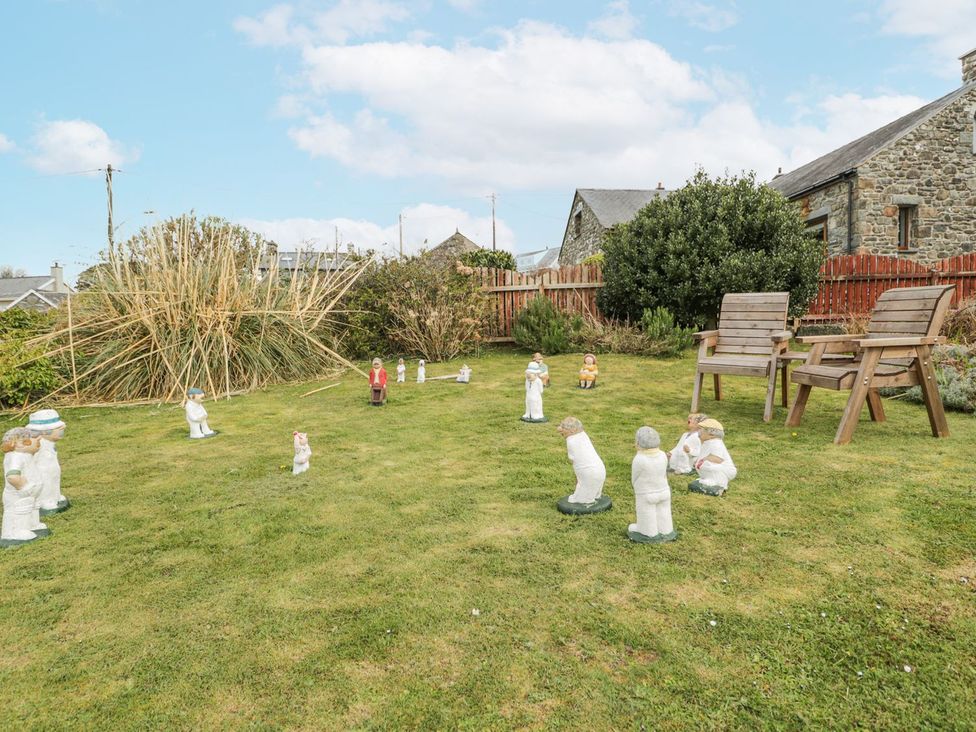 A garden with figurines and wooden chairs at Happy Landing in Harlech