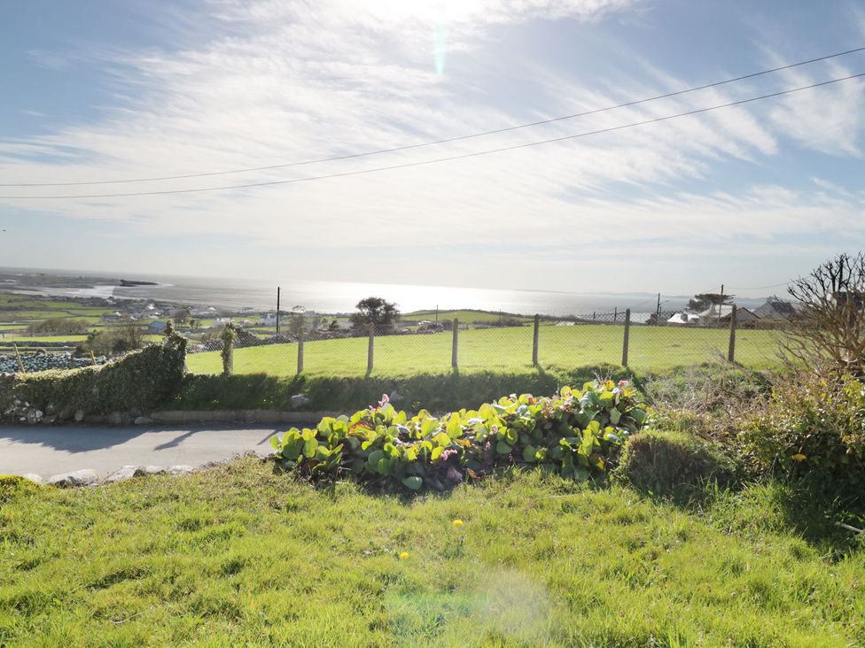 An outdoor view of the ocean with grass and plants at Happy Landing in Harlech