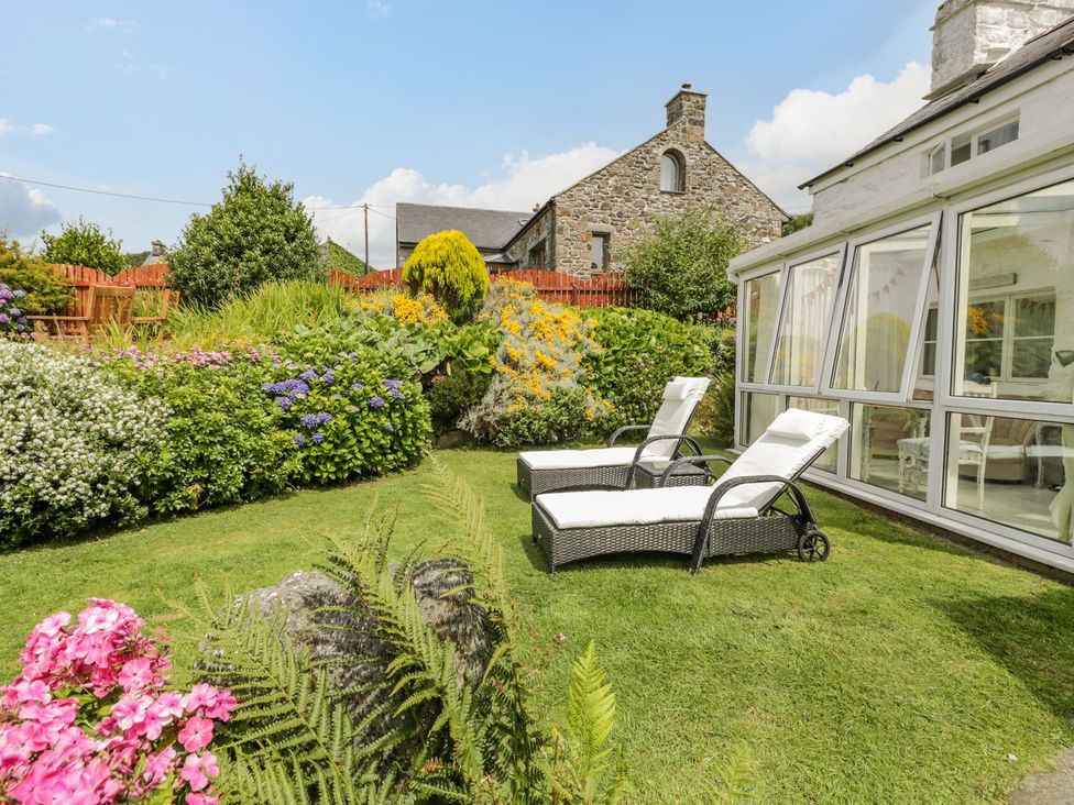 A garden with deck chairs and flowers at Happy Landing in Harlech