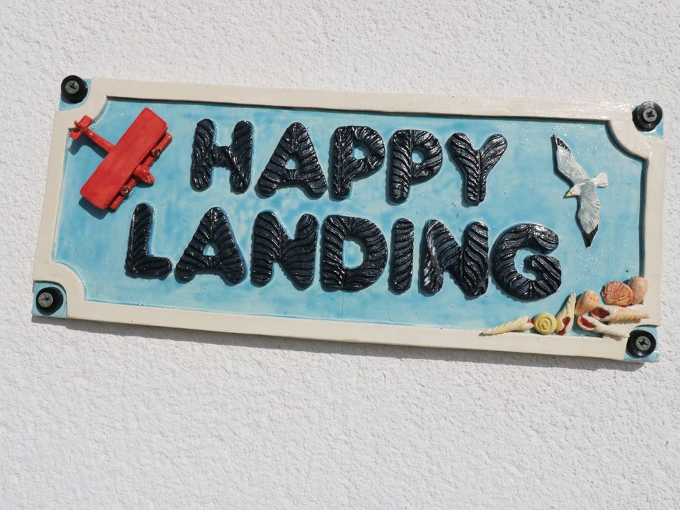 A decorative sign that reads Happy Landing at Happy Landing in Harlech