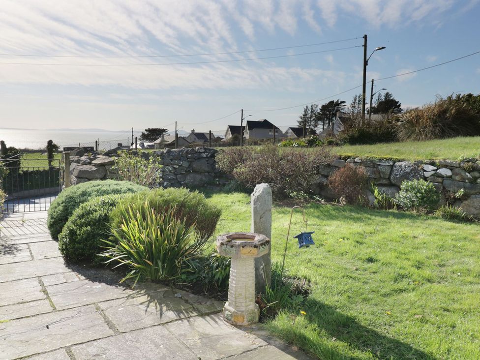 A garden with plants and a stone bird bath at Happy Landing in Harlech