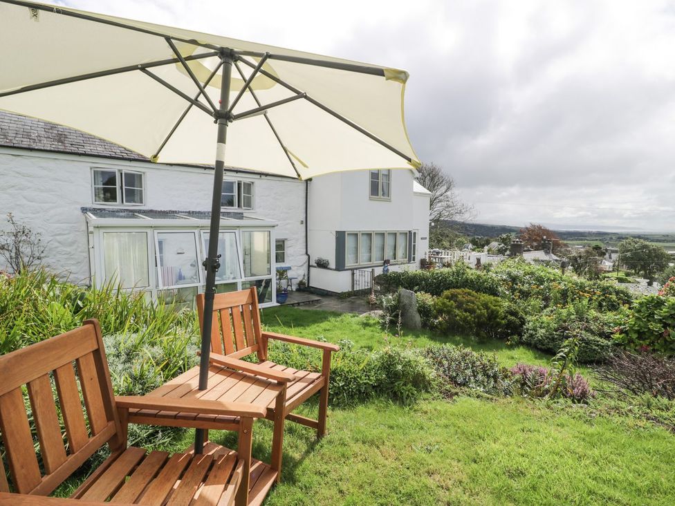 A garden with chairs and an umbrella at Happy Landing in Harlech