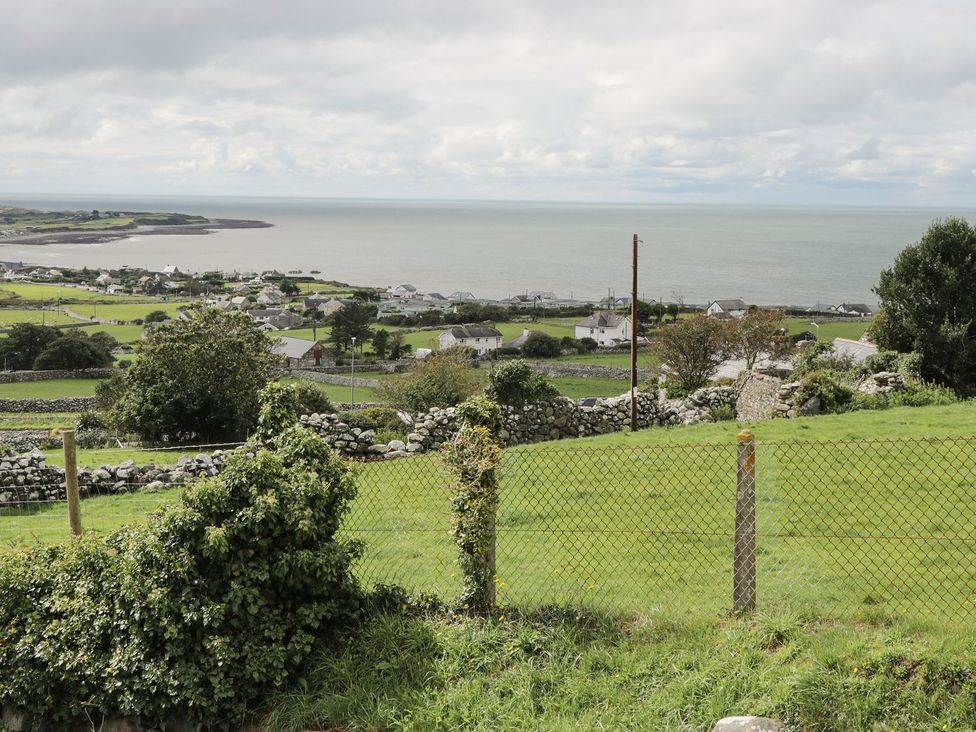 A view of the ocean and houses from a grassy area at Happy Landing in Harlech