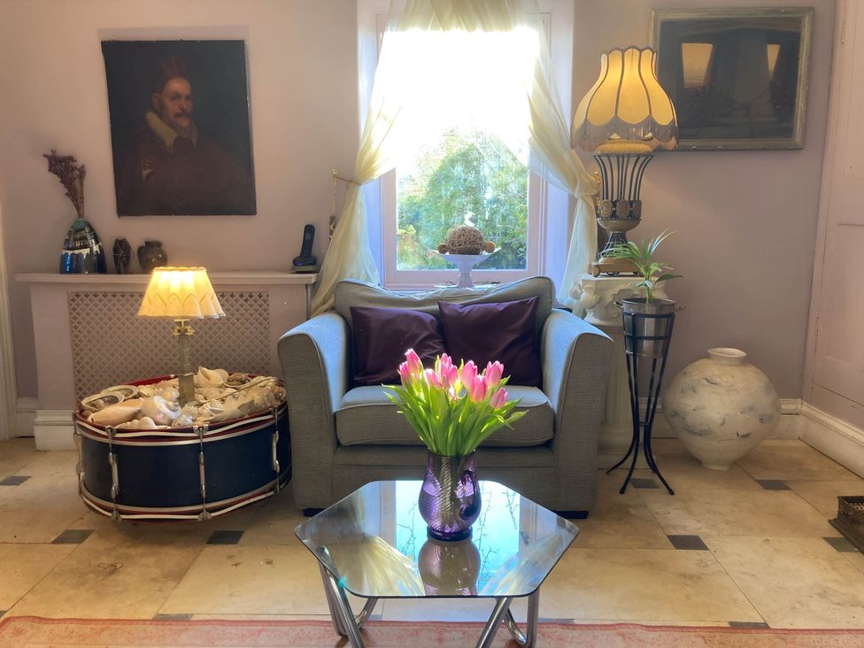 A living room with a sofa and flowers on a table at Groves Hall Garden Apartment Whitby