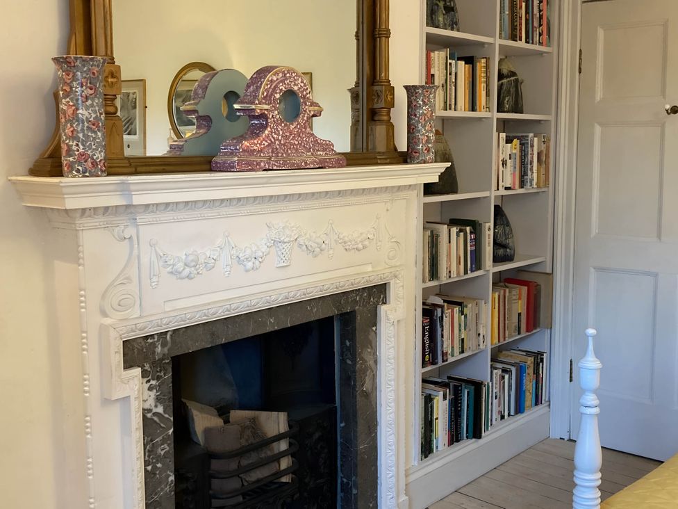 A living room with a fireplace and bookshelf at Groves Hall Garden Apartment Whitby