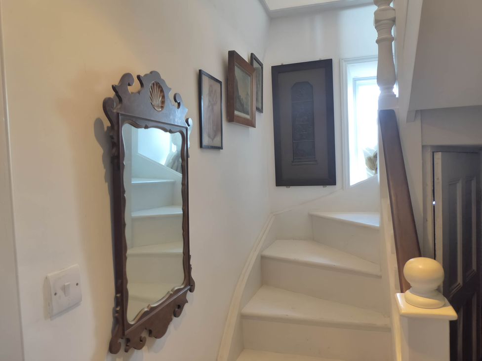 A staircase with a mirror and framed pictures at Groves Hall Garden Apartment Whitby