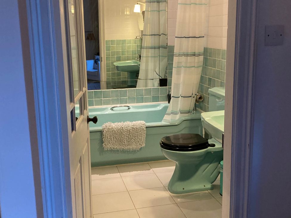 A bathroom with a bath tub and toilet at Groves Hall Garden Apartment Whitby