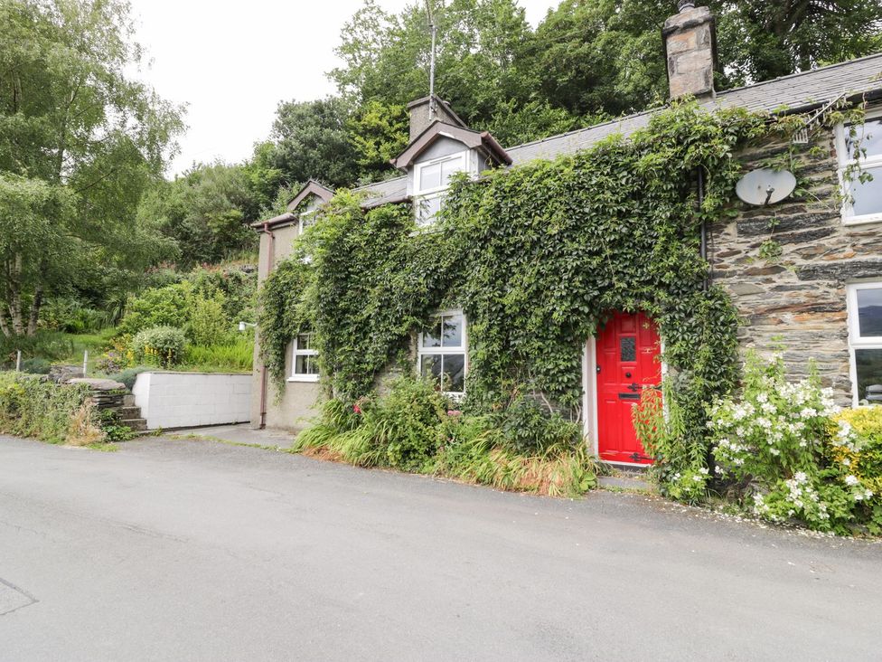 An exterior view of a house with a red door at Bodorwel Cottage in Penrhyndeudraeth
