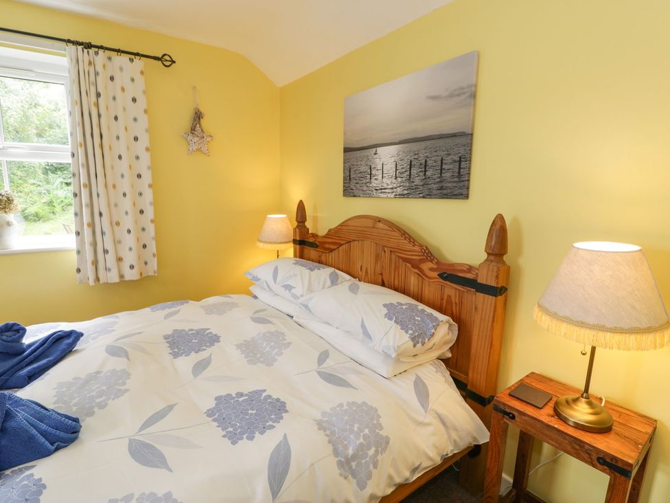 A bedroom with a bed and curtains at Bodorwel Cottage in Penrhyndeudraeth