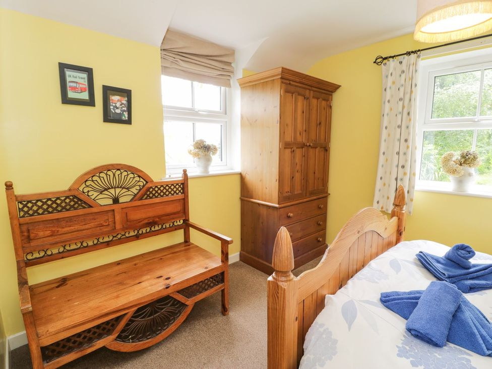 A bedroom with a bench and wardrobe at Bodorwel Cottage in Penrhyndeudraeth