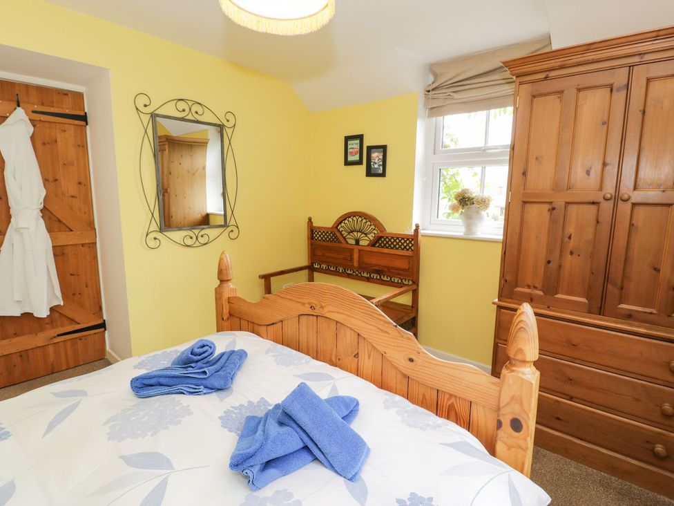 A bedroom with a bed and wooden furniture at Bodorwel Cottage Penrhyndeudraeth