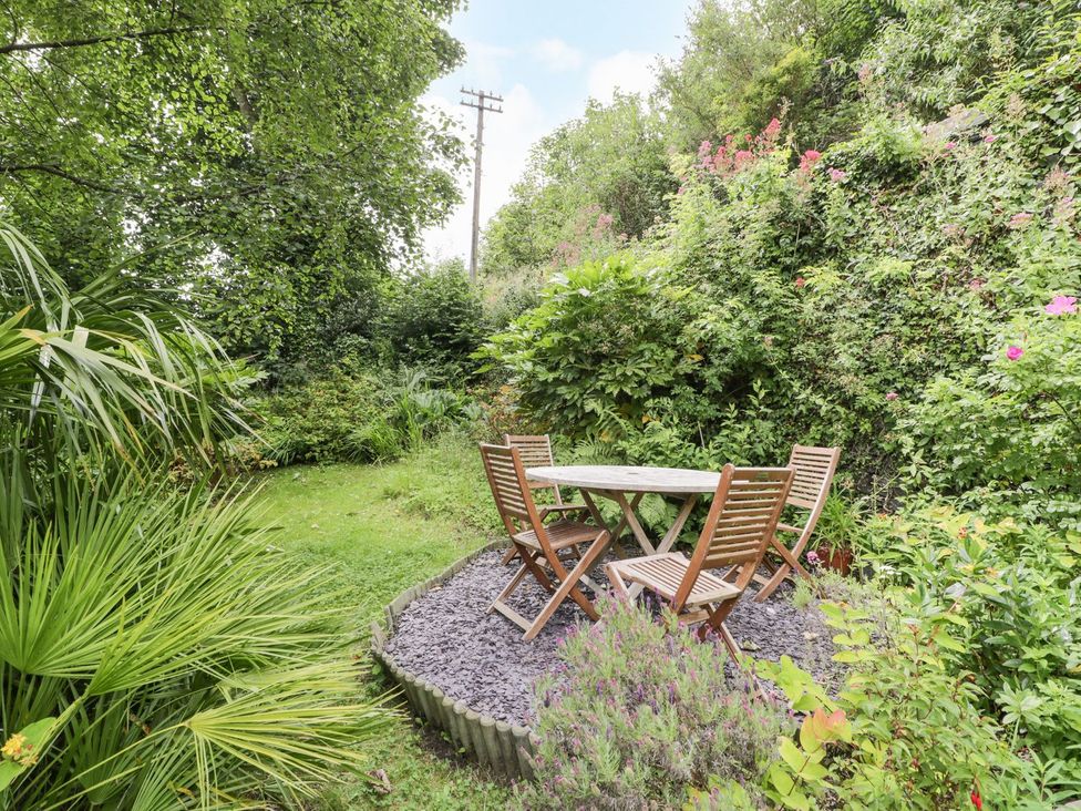 A garden with a table and chairs surrounded by plants at Bodorwel Cottage Penrhyndeudraeth