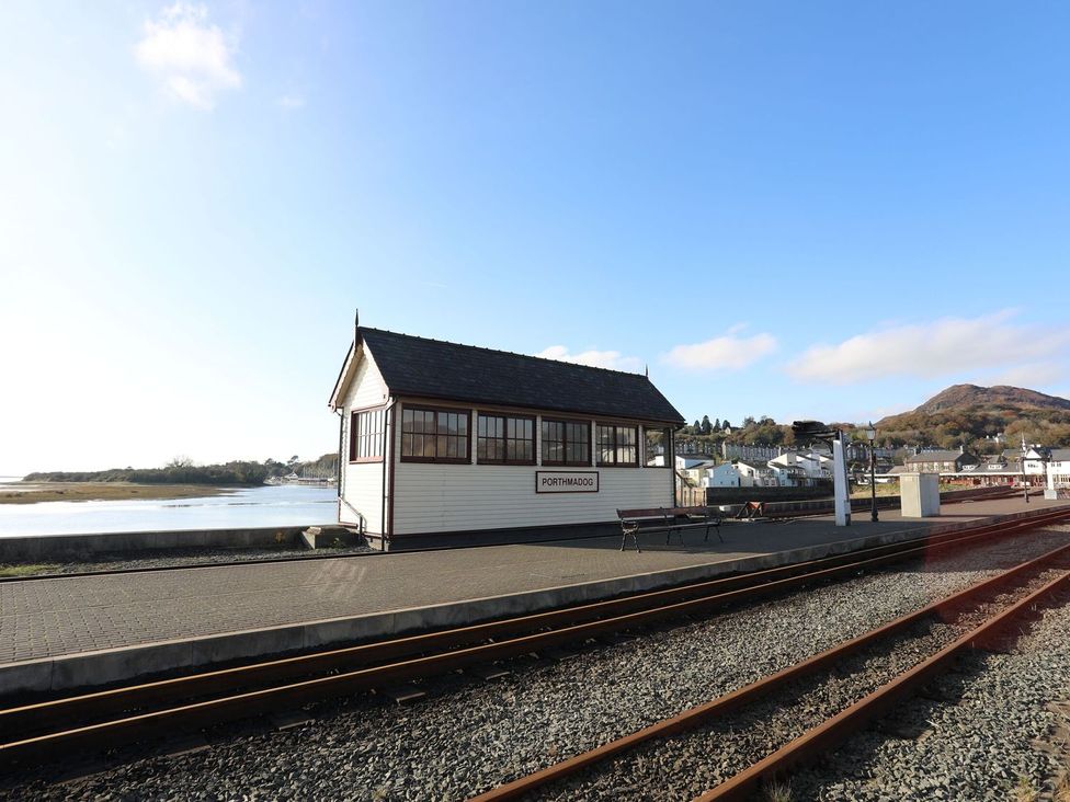 A station building with railway tracks and a sign at Porthmadog