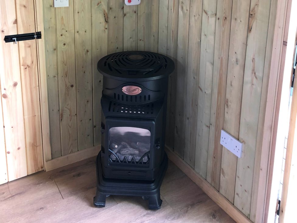 A stove in a wooden room at The Peacock Shepherds Hut at Hafoty Boeth, Corwen