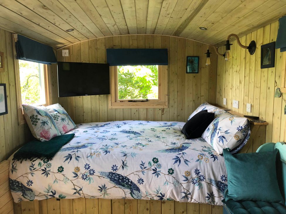 A sleeping area with a bed and television at The Peacock Shepherds Hut at Hafoty Boeth in Corwen