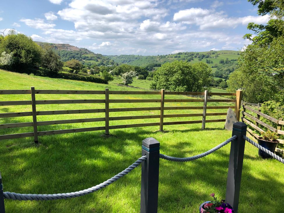 An outdoor area with a fence and a view of trees and mountains at The Peacock Shepherds Hut at Hafoty Boeth, Corwen