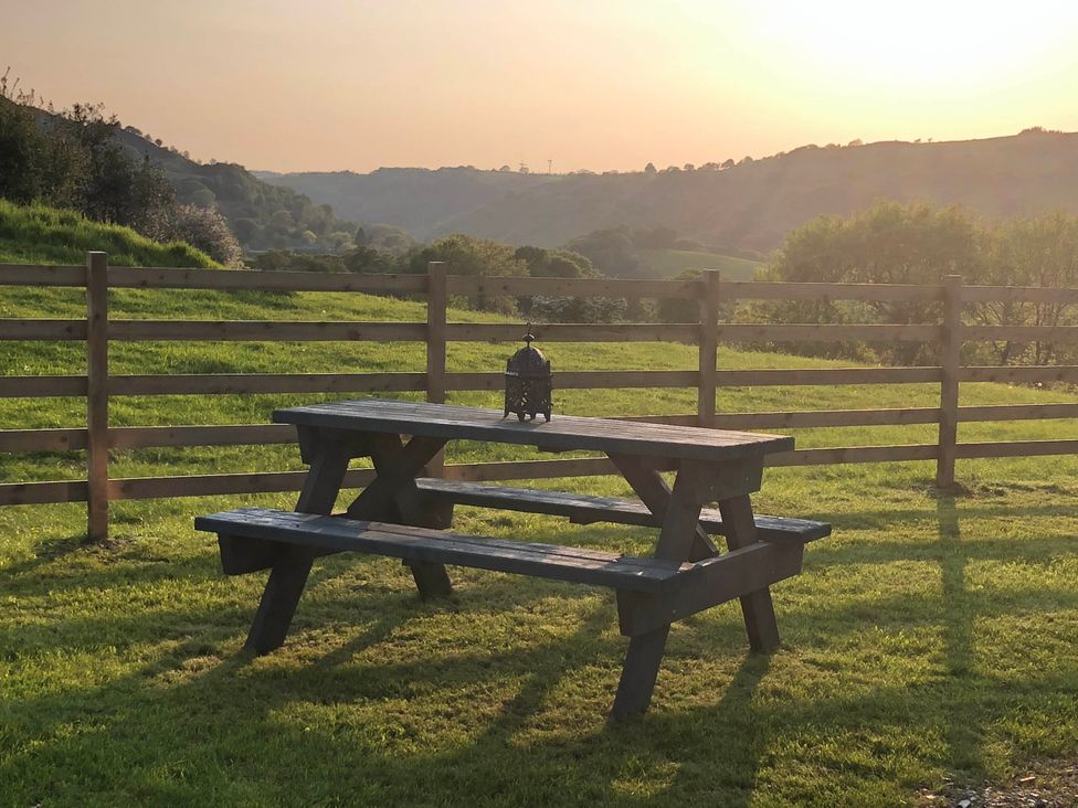 A picnic table with a lantern in a field at The Peacock Shepherds Hut at Hafoty Boeth Corwen
