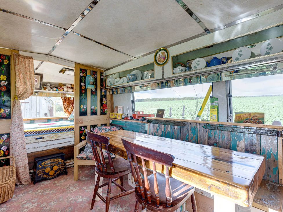 A kitchen with a wooden table and chairs at 2 x Double Bed Glamping Wagon at Dalby Forest, Scarborough