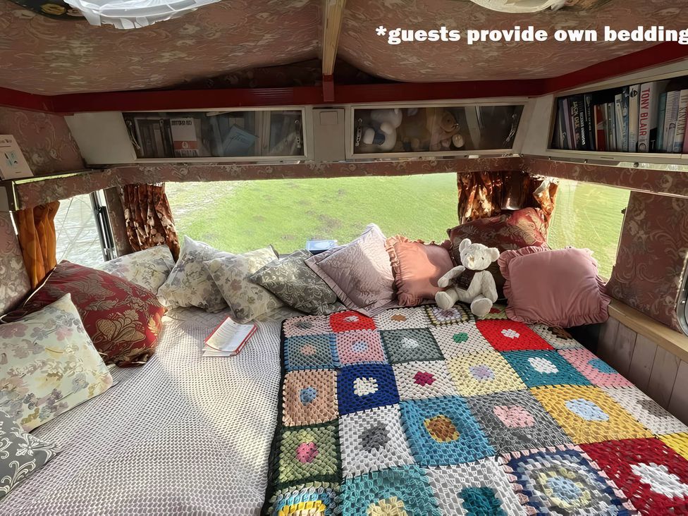 A sleeping area with a bed and cushions at 2 x Double Bed Glamping Wagon at Dalby Forest, Scarborough