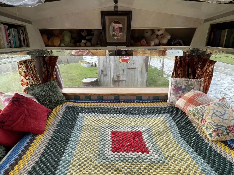 A living room with a bed and cushions at 2 x Double Bed Glamping Wagon at Dalby Forest, Scarborough