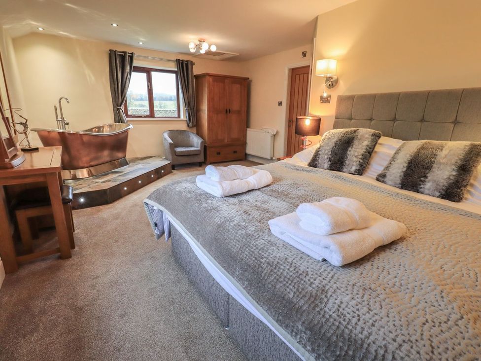 A bedroom featuring a bed, bath tub, and chair at Orcaber Farm Retreat in Lancaster