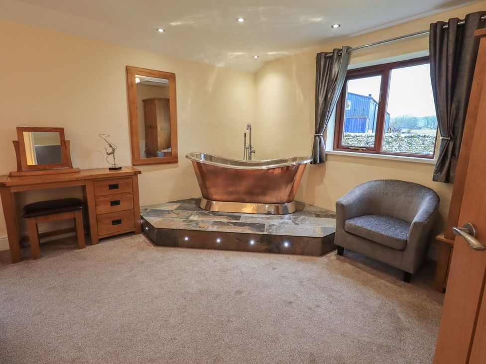 A bathroom with a bathtub and a dressing table at Orcaber Farm Retreat in Lancaster