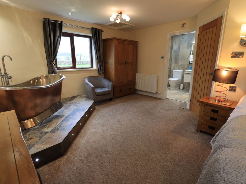 A bedroom with a bathtub and armchair at Orcaber Farm Retreat in Lancaster