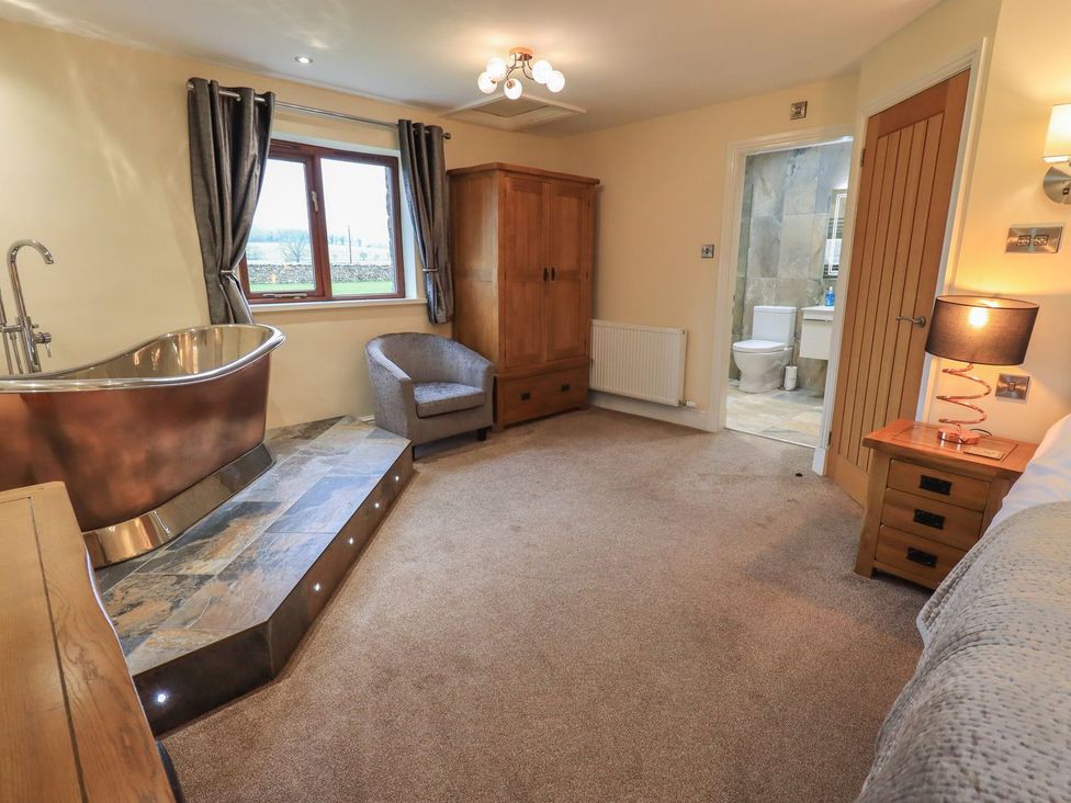A bedroom with a bathtub and an armchair at Orcaber Farm Retreat in Lancaster