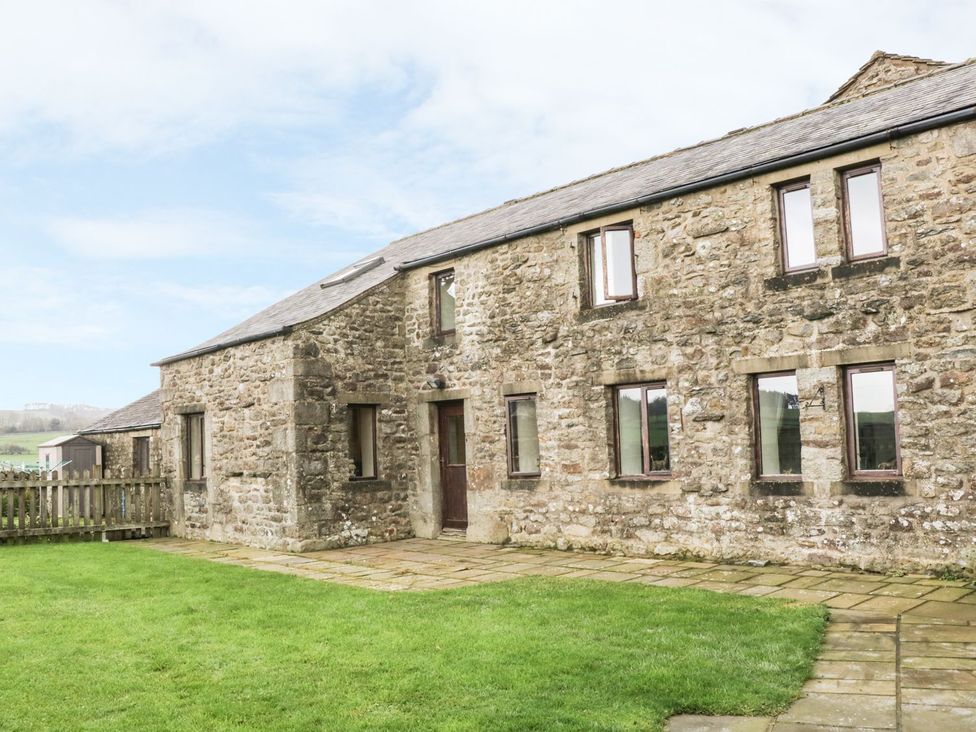 A stone building with windows and a door surrounded by grass at Orcaber Farm Barn Lancaster