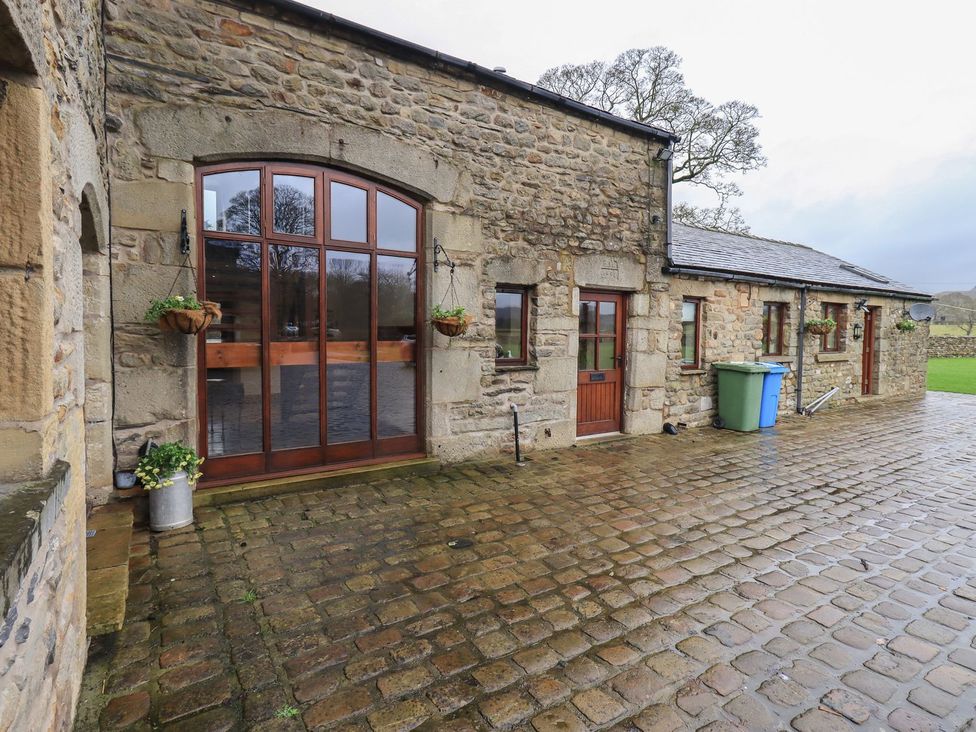 An outdoor area with stone walls and wooden doors at Orcaber Farm Barn in Lancaster