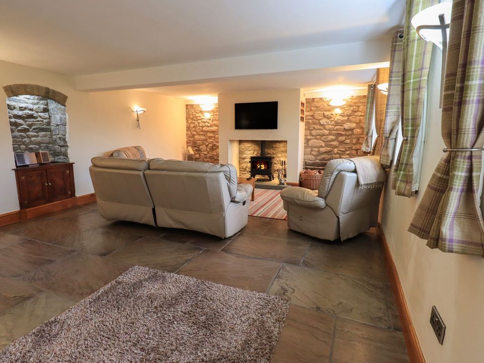 A living room with a sofa and fireplace at Orcaber Farm Barn in Lancaster