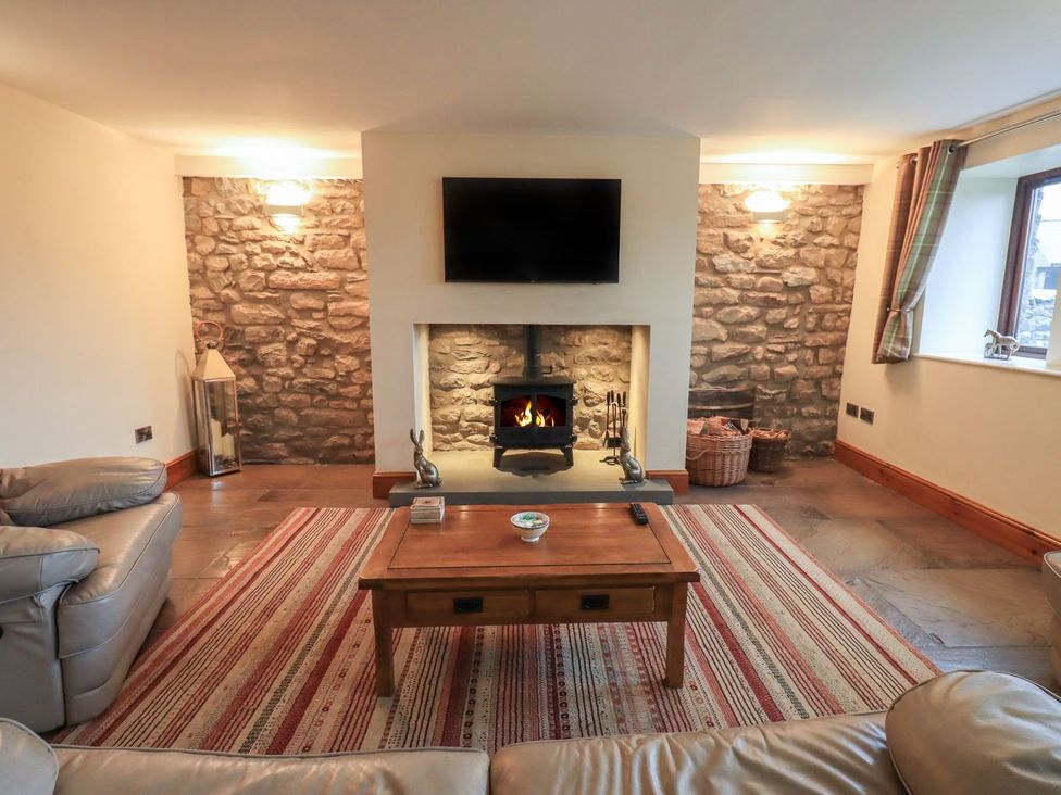 A living room with a fireplace and television at Orcaber Farm Barn in Lancaster