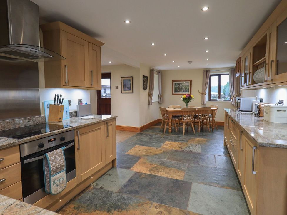 A kitchen with a stove and dining table at Orcaber Farm Barn in Lancaster