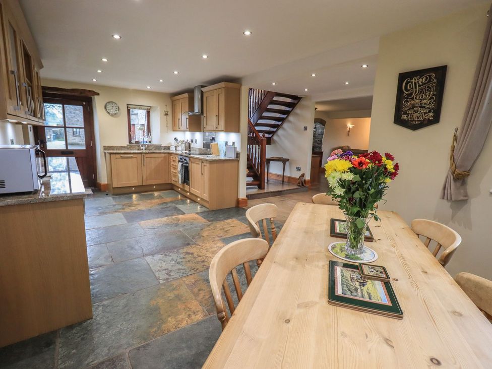 A kitchen with a dining table and flowers at Orcaber Farm Barn in Lancaster