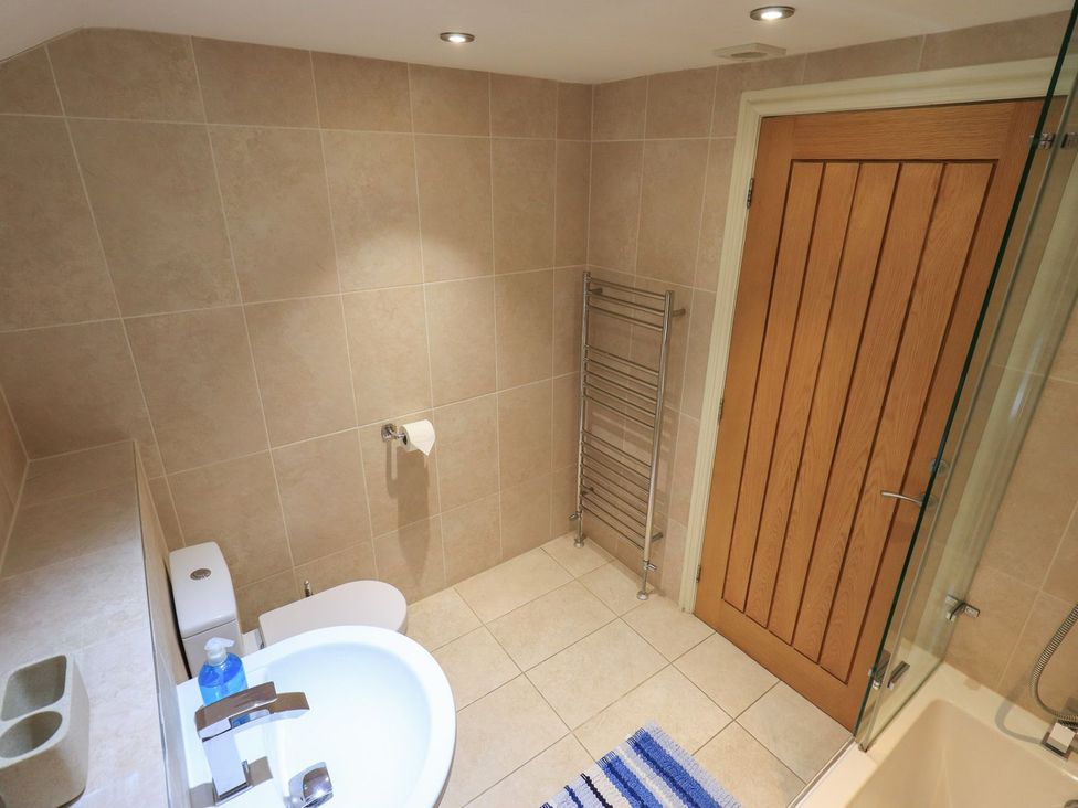 A bathroom with a bath tub, toilet, and sink at Orcaber Farm Barn in Lancaster