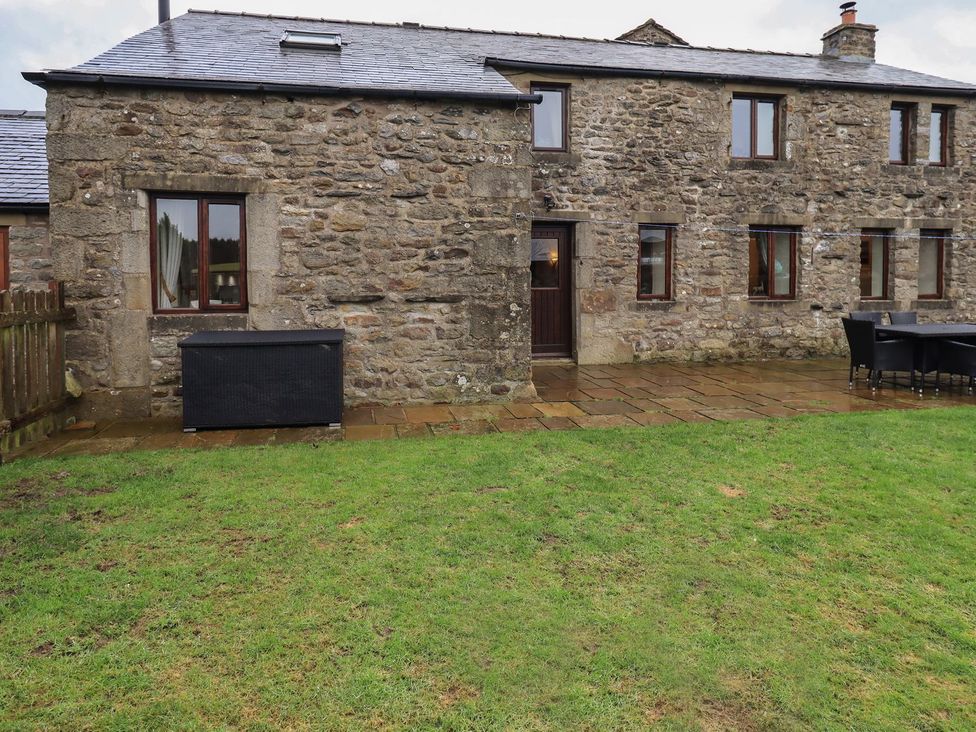 An outdoor area with a stone wall and patio at Orcaber Farm Barn in Lancaster